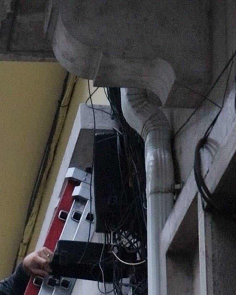 A TF Franco ladder against a building facade, next to the network box